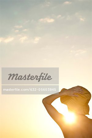 Femme à l'extérieur silhouettée sur le coucher du soleil