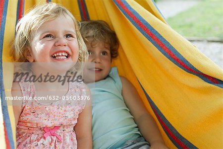 Young siblings sitting together in hammock