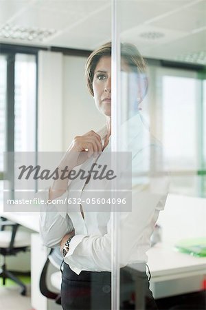Businesswoman standing behind glass partition in office