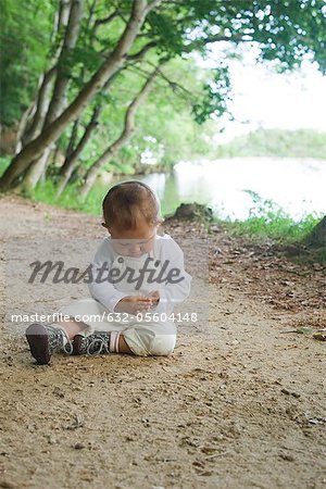 Petite fille assise sur le chemin de terre dans les bois