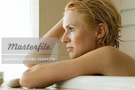 Mid-adult woman relaxing in bath, contemplatively looking away, portrait