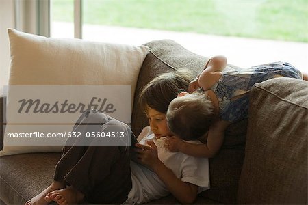 Boy relaxing on sofa, looking at digital tablet