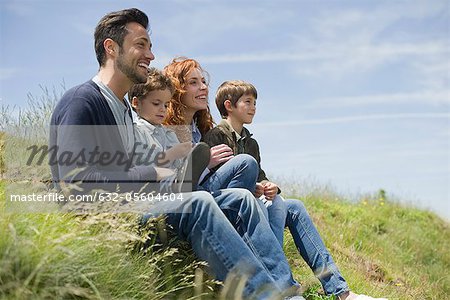 Parents with young boys sitting on meadow