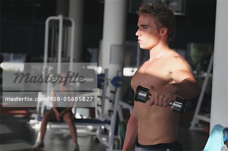 Young Man Taking Physical Training with Dumbbell