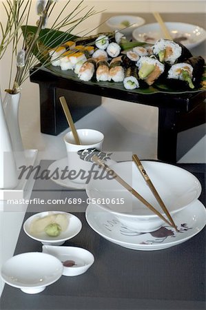 Sushi, chopsticks and bowls on table