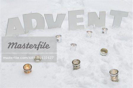 Tea candles and word advent in snow