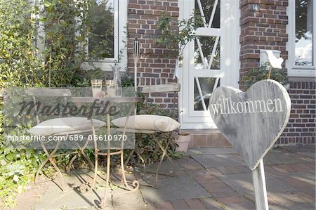 Sign and table with chairs at house entrance