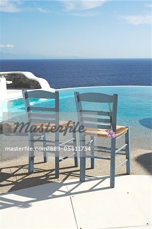 Two chairs by the poolside above the ocean