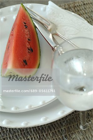 Slice of watermelon on plate and glass of water Slice of watermelon on plate and glass of water