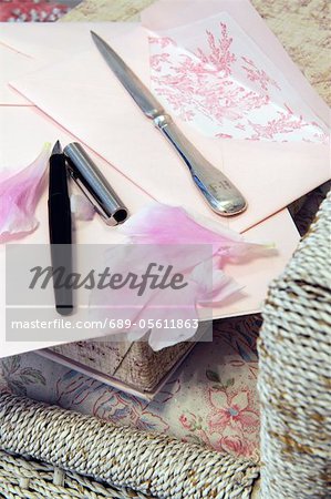 Letter, rose petals, stylograph and letter opener on chair