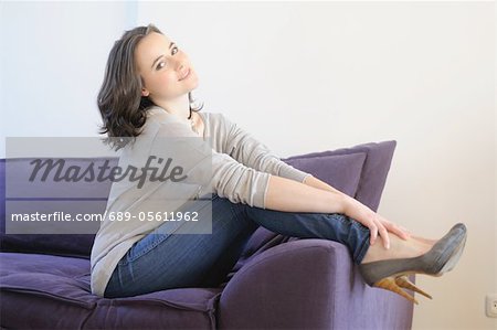 Jeune femme sur le canapé en mettant ses pieds vers le haut