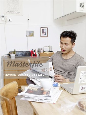 Man reading newspaper at home