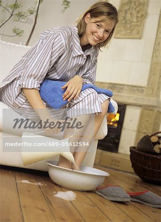 Femme en pyjama en prenant le bain de pieds