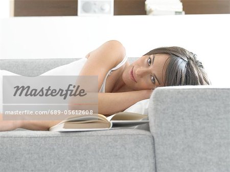 Woman lying on couch with book