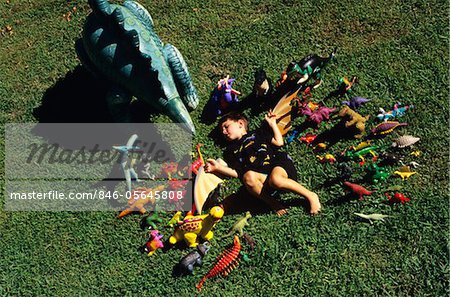 1990s FOUR YEAR OLD BOY SURROUNDED WITH DINOSAUR TOY COLLECTION
