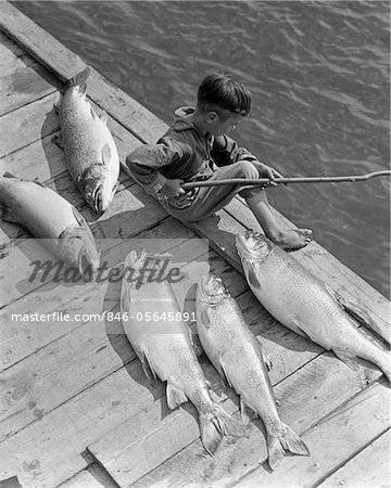 1930s BOY SEATED ON DOCK WITH 5 LARGE FISH FISHING WITH STICK POLE