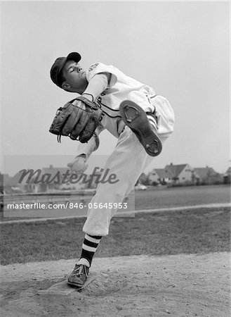 1950s TEEN IN BASEBALL UNIFORM WINDING UP FOR PITCH