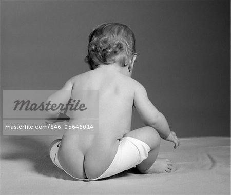 1960s BACK VIEW OF BABY SEATED WITH DIAPER COMING OFF AND BARE BOTTOM SHOWING