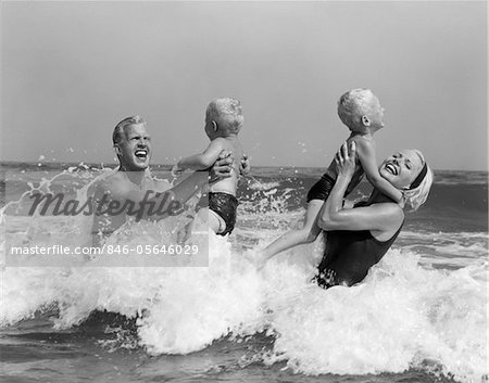 1970s - 1960s FAMILY FATHER MOTHER HOLDING UP A TWIN SONS IN THE OCEAN SURF
