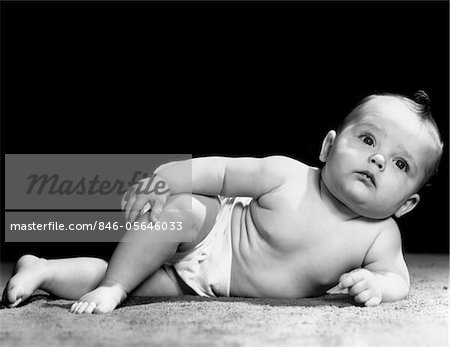 1940s BABY LAYING ON SIDE PROPPED UP ON ELBOW LEGS CROSSED DISTRACTED EXPRESSION