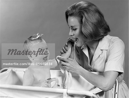 1960s MOTHER WASHING BABY IN BABY BATH TUB
