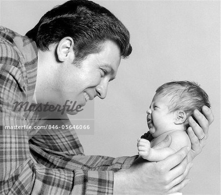 1970s CLOSE-UP PORTRAIT OF SMILING FATHER HOLDING POUTING NEWBORN