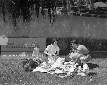 1950s FAMILY MOTHER FATHER SON DAUGHTER PICNICKING BY LAKE OUTDOOR