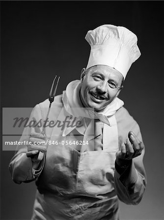 1950s MAN CHEF SMILING WITH EXPRESSIVE HANDS LOOKING AT CAMERA INDOOR