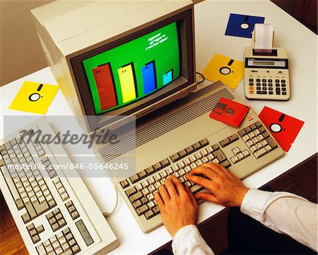 1980s MALE HANDS ON COMPUTER KEYBOARD WITH MONITOR FLOPPY DISKS CALCULATOR