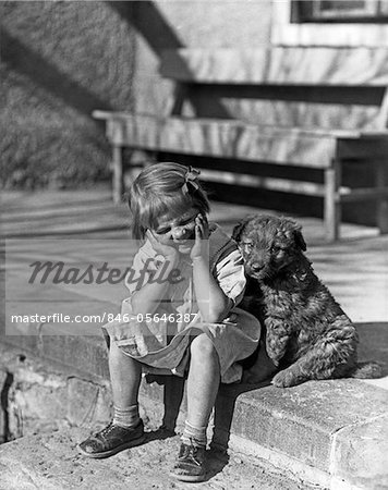 1930s LITTLE GIRL SITTING ON PORCH STOOP FUNNY EXPRESSION HANDS UP TO HER FACE BESIDE HER DOG