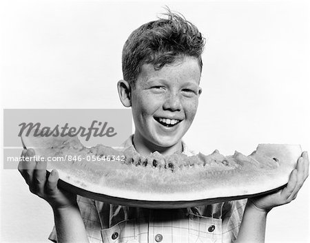 1940S - 1950S LÄCHELND BOY HOLDING GROßES STÜCK WASSERMELONE ESSEN