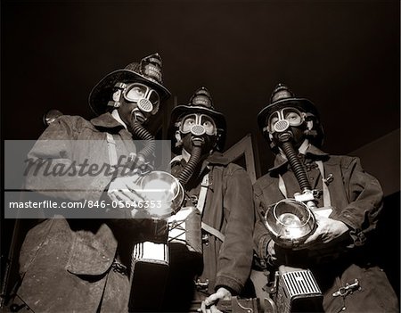 1950s TRIO OF RESCUE SQUAD FIREMEN WEARING RESPIRATOR MASKS CARRYING FLASHLIGHTS AND FIRE EQUIPMENT