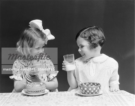 1930ER JAHREN ZWEI LÄCHELND MÄDCHEN TRINKSCHALE MILCH GETREIDE ESSEN LACHEN REDEN