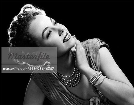 1950s GLAMOROUS WOMAN WEARING FOUR STRAND PEARL NECKLACE AND MATCHING BRACELET