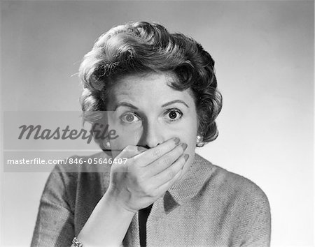 1950s HEAD SHOT OF STARTLED WOMAN COVERING MOUTH WITH HAND