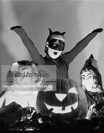 1950s 3 CHILDREN IN COSTUMES AROUND A CARVED PUMPKIN JACK-O-LANTERN