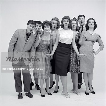 1960s GROUP OF 8 FASHIONABLE TEENS STANDING FULL LENGTH LOOKING AMAZED