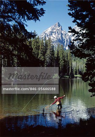 1960s MAN FISHING AT STRING LAKE GRAND TETON NATIONAL PARK WYOMING