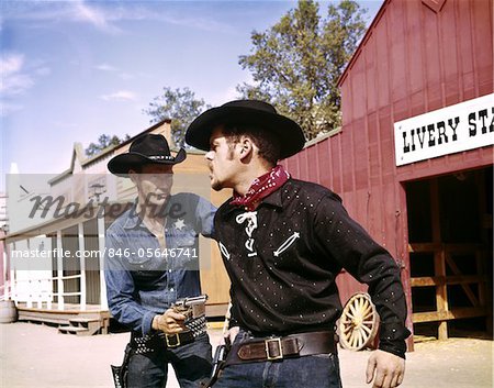 1960s COWBOY SHERIFF WITH BADGE DRAWS GUN ARRESTS GUNFIGHTER IN FRONT OF LIVERY STABLE