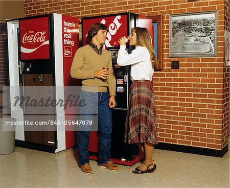 1980s TEENAGE BOY GIRL STANDING AT SODA VENDING MACHINES