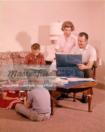1960s PARENTS MOTHER FATHER 2 BOYS SONS & GIRL DAUGHTER IN LIVING ROOM LOOKING AT NEW HOUSE BLUEPRINT PLANS