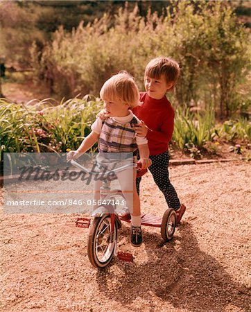 1960s - 1970s YOUNG BOY AND GIRL PLAYING TOGETHER RIDING TRICYCLE