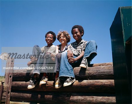 ANNÉES 1960 - ANNÉES 1970 3 GARÇONS ASSIS CONNECTER CLÔTURE SOURIANT PORTER JEANS BLEU 2 AFRO-AMÉRICAIN 1 CAUCASIENNE