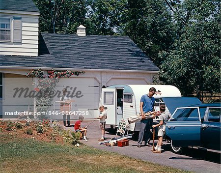 1960s FAMILY FATHER MOTHER SONS LOADING CAR AND TRAILER FOR OUTDOOR SUMMER VACATION