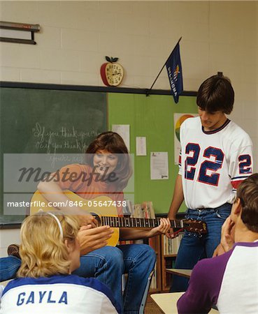 ANNÉES 1980 COLLÈGE ÉTUDIANTS EN SALLE DE CLASSE PLAYING GUITAR