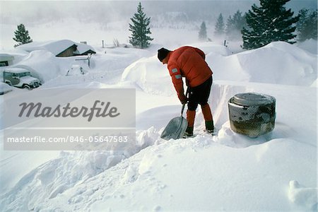 1980s MAN SHOVELING SNOW OFF HOUSE ROOF MAMMOTH LAKES CALIFORNIA USA