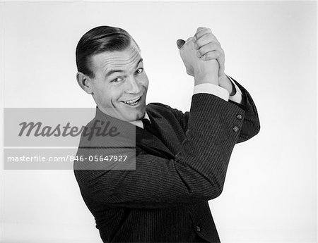 1950s - 1960s SMILING BUSINESSMAN HANDS CLASPED OVERHEAD IN SUCCESSFUL WINNER SYMBOLIC SIGN