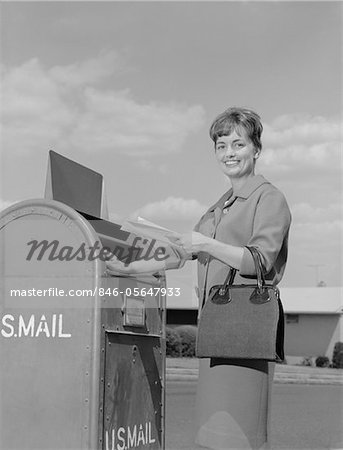 1960s SMILING WOMAN DROPPING LETTERS IN POSTAL MAIL BOX