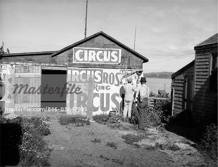 1920s BILL POSTERS STICKING SIGNS ON THE SIDE OF A BARN ADVERTISING A TRAVELING CIRCUS