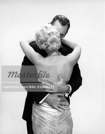 1950s - 1960s KISSING COUPLE BLOND WOMAN BACKLESS SATIN EVENING DRESS MAN EMBRACING FROM BEHIND